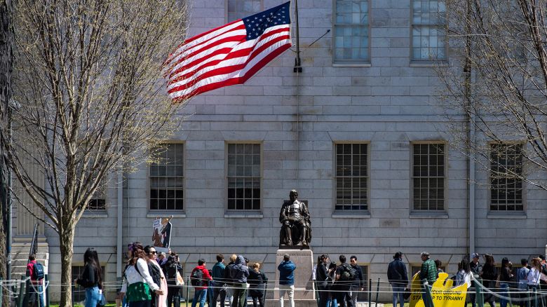 Demonstrators with signs stand around the John Harvard Statue in Harvard Yard after a rally was held against President Donald Trump's attacks on Harvard University at Harvard University in Cambridge, Massachusetts on April 17, 2025.