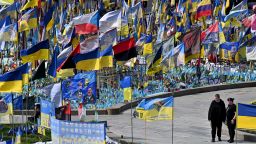 A couple walks by flags and portraits of fallen servicemen at a makeshift memorial for the fallen Ukrainian and foreign fighters, at the Independence Square in Kyiv on April 19, 2025, amid the Russian invasion of Ukraine. Russian President Vladimir Putin on Saturday announced an Easter truce in the conflict in Ukraine starting this evening and lasting till midnight on April 20, 2025.