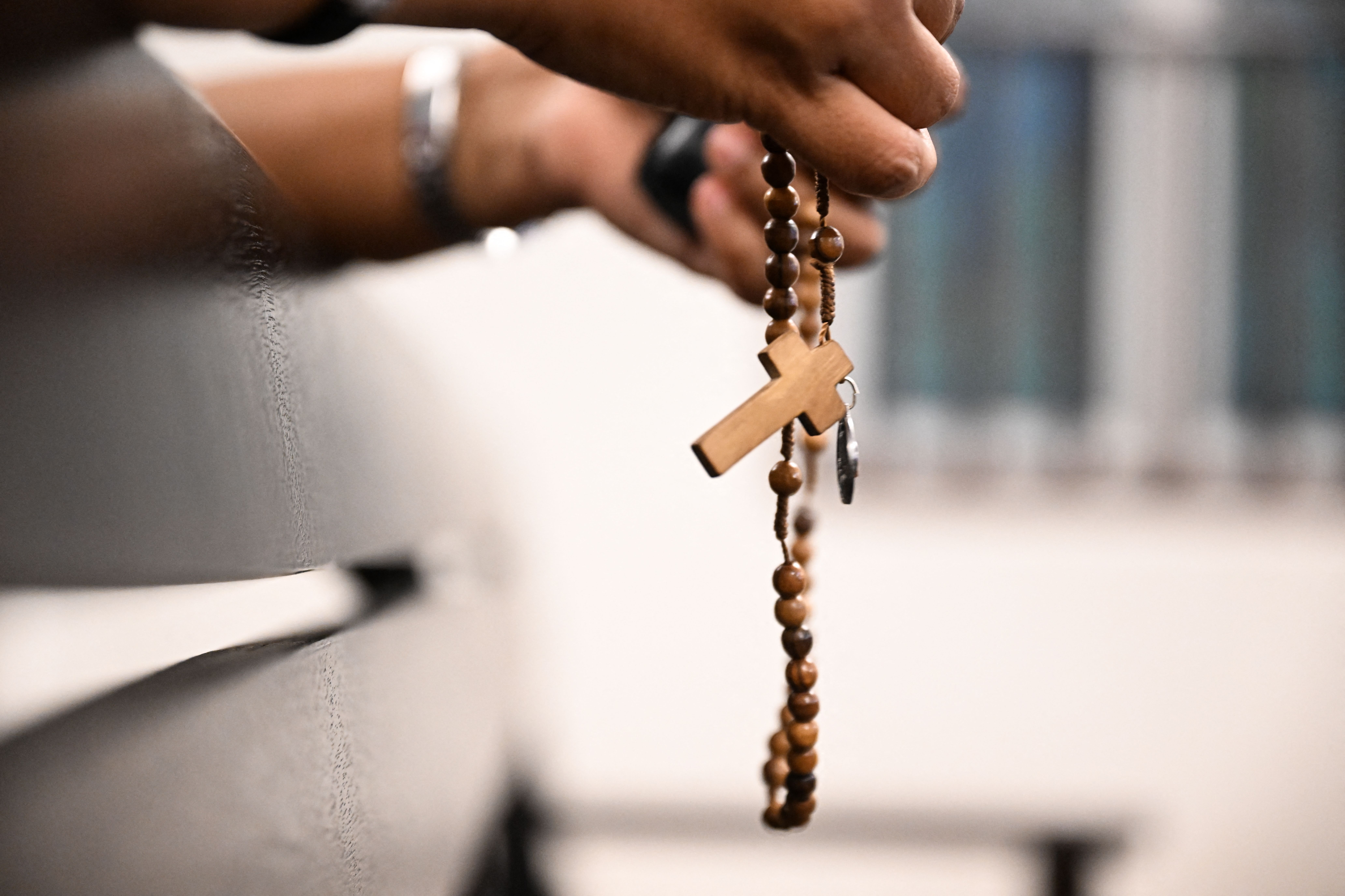 A person holds a rosary with a cross during Mass at the Sacred Heart Church in Bentong, Malaysia.