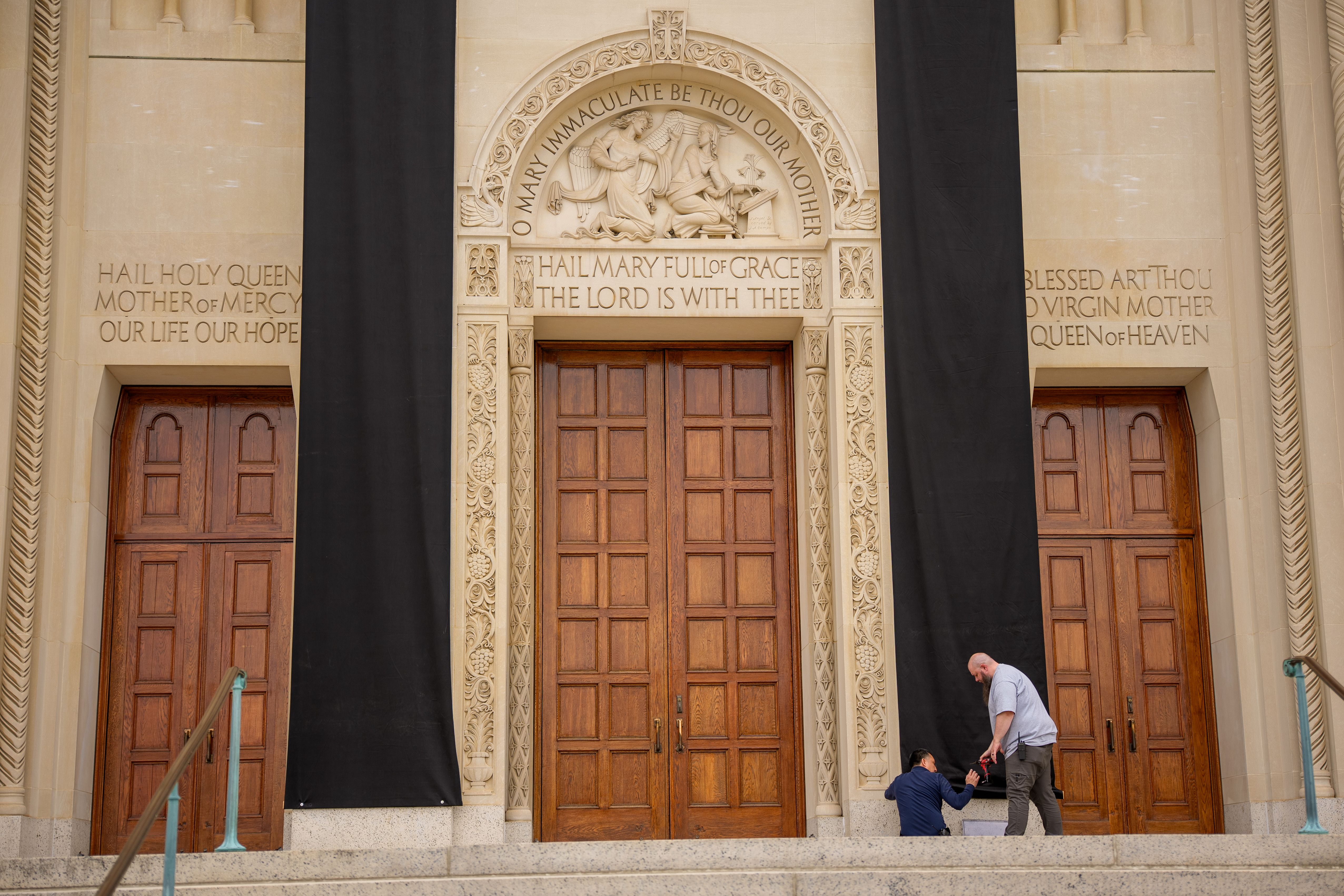 Workers hang black drapes over the front of the Basilica of the National Shrine of the Immaculate Conception in Washington, DC.