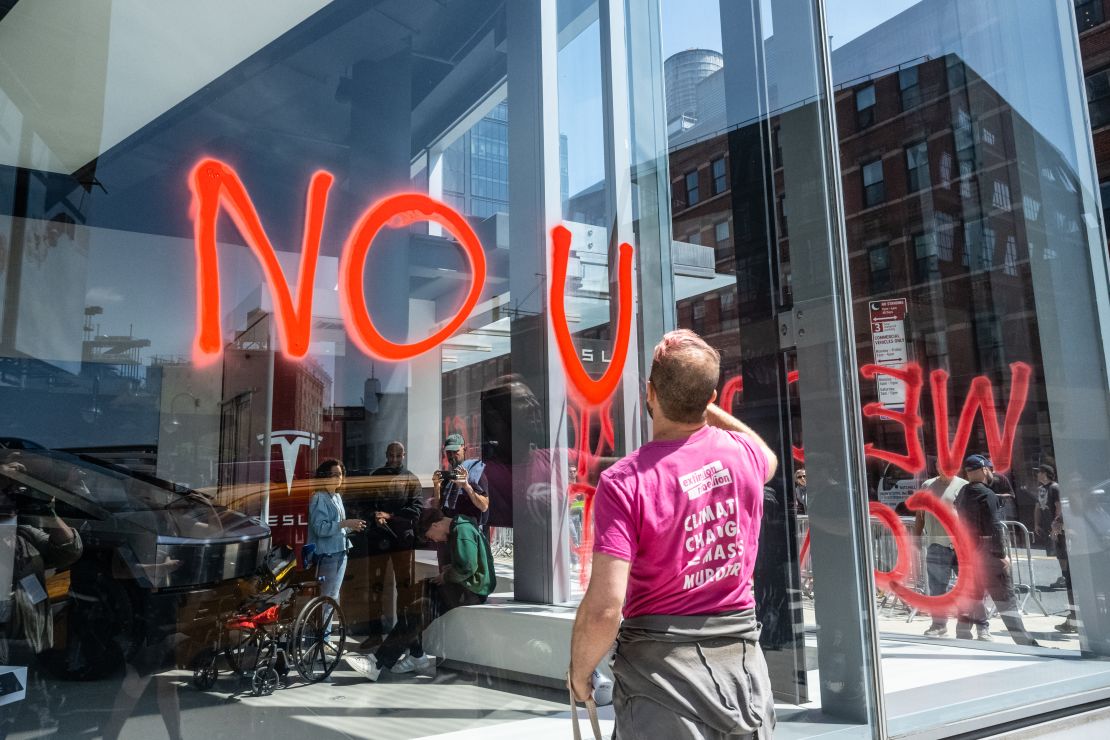 Members of the climate protest group Extinction Rebellion spray-paint anti-DOGE messages on the outside of a Tesla showroom in New York City, on April 22.
