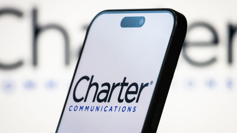 CHONGQING, CHINA - APRIL 20: In this photo illustration, the Charter Communications logo is displayed on a smartphone screen, with the company's branding visible in the background, on April 20, 2025, in Chongqing, China. Charter Communications is a leading American broadband connectivity and cable operator known for its Spectrum-branded internet, TV, mobile, and voice services. (Photo by Cheng Xin/Getty Images)