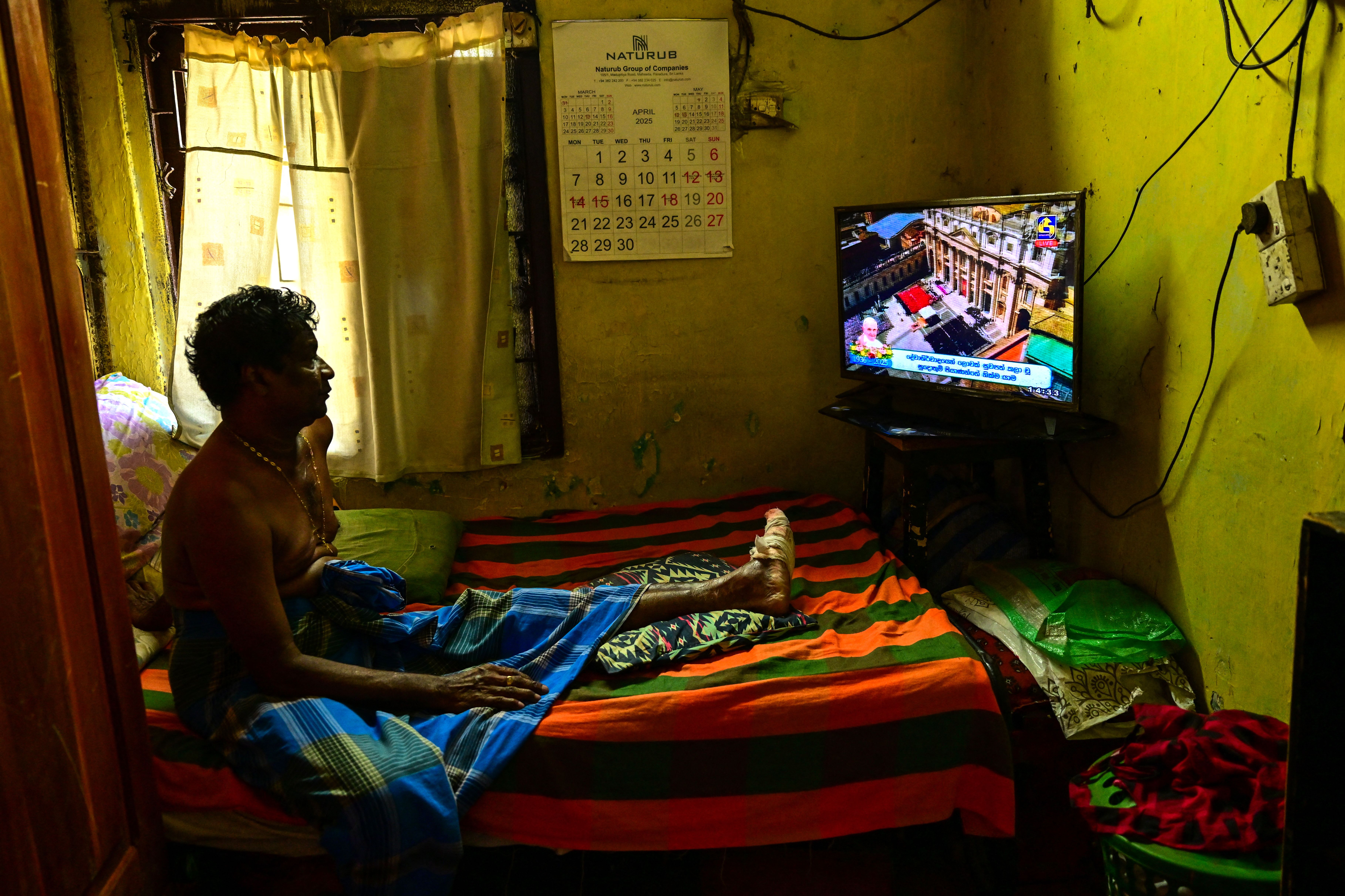 A Catholic man watches a live telecast of the pope's funeral from Colombo, Sri Lanka.