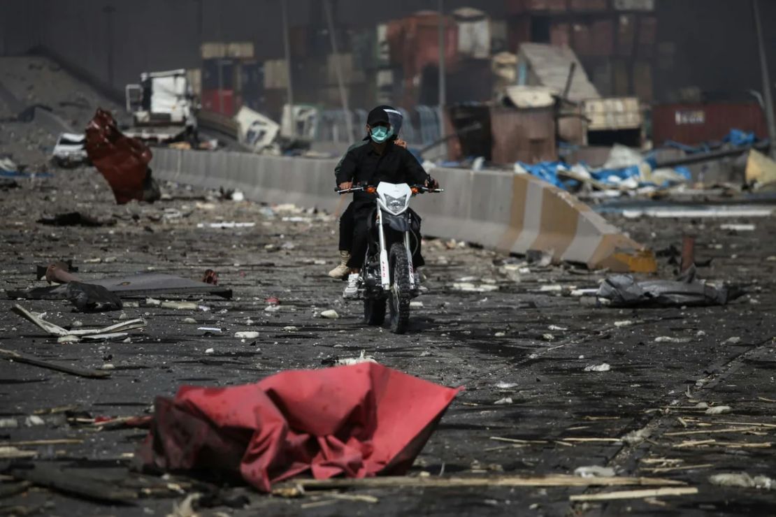 Hombres montan una motocicleta en medio de la devastación.