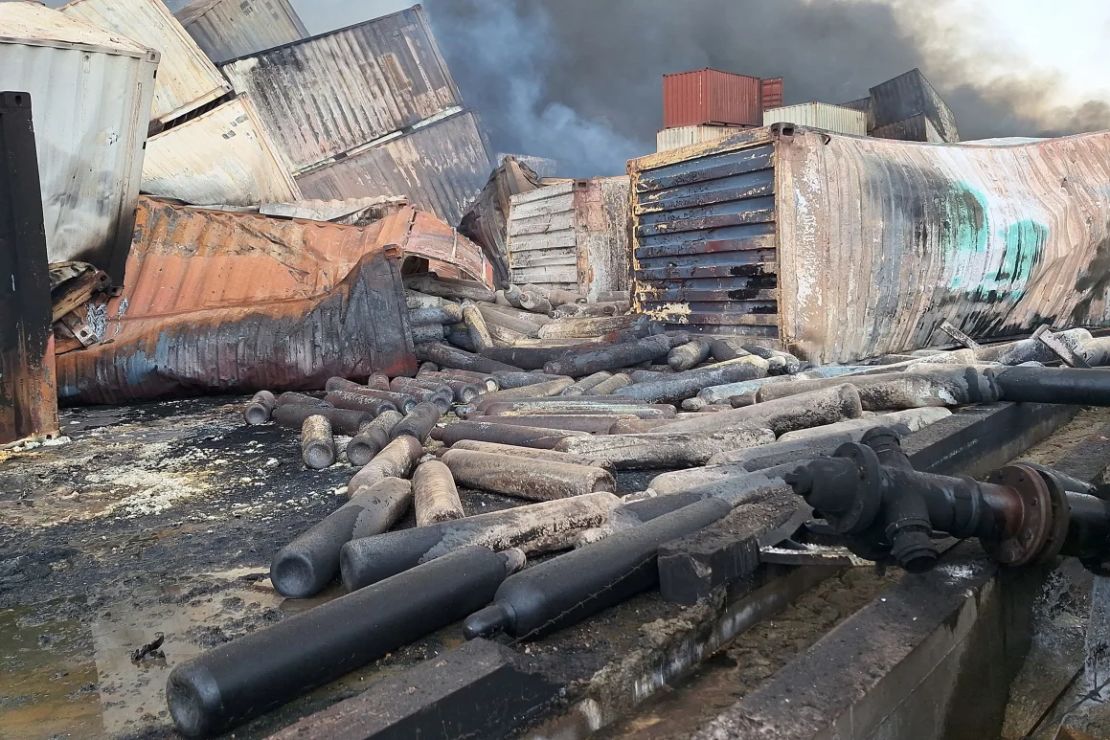 Mercancías y contenedores carbonizados yacen en el sitio de la mortal explosión en el puerto.