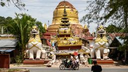 This photo taken on April 12, 2025 shows people driving past the debris of a damaged Buddha statue in Inwa on the outskirts of Mandalay, following the devastating March 28 earthquake.