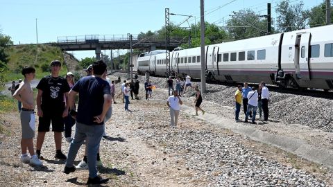 Los pasajeros permanecen junto a un tren de alta velocidad AVE de RENFE detenido cerca de Córdoba, España, el lunes.