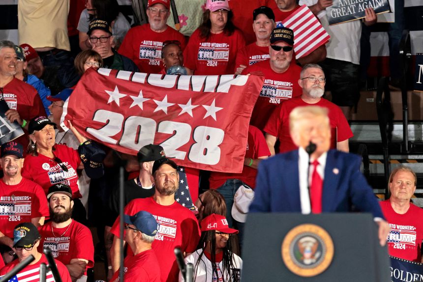 People hold up a Trump 2028 banner as President Donald Trump delivers his 100th Day in office achievement speech in Warren, Michigan, on April 29, 2025.