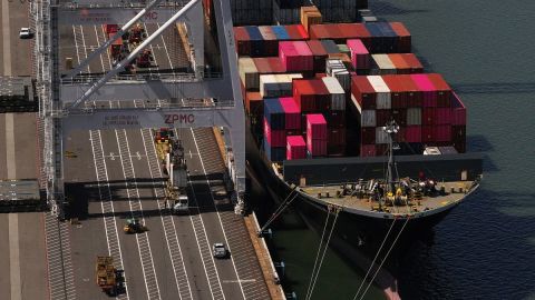 En una vista aérea, un contenedor de carga es levantado de un buque portacontenedores atracado en el Puerto de Oakland el 28 de abril de 2025 en Oakland, California. Los economistas de la Reserva Federal revisaron al alza sus proyecciones de inflación para este año y redujeron sus expectativas de crecimiento económico.
