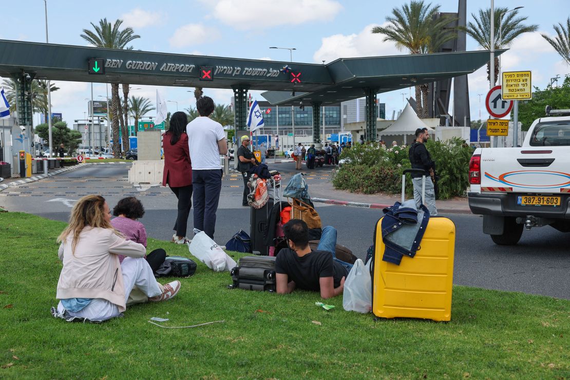 Travelers wait outside Ben Gurion Airport as flights are interrupted.