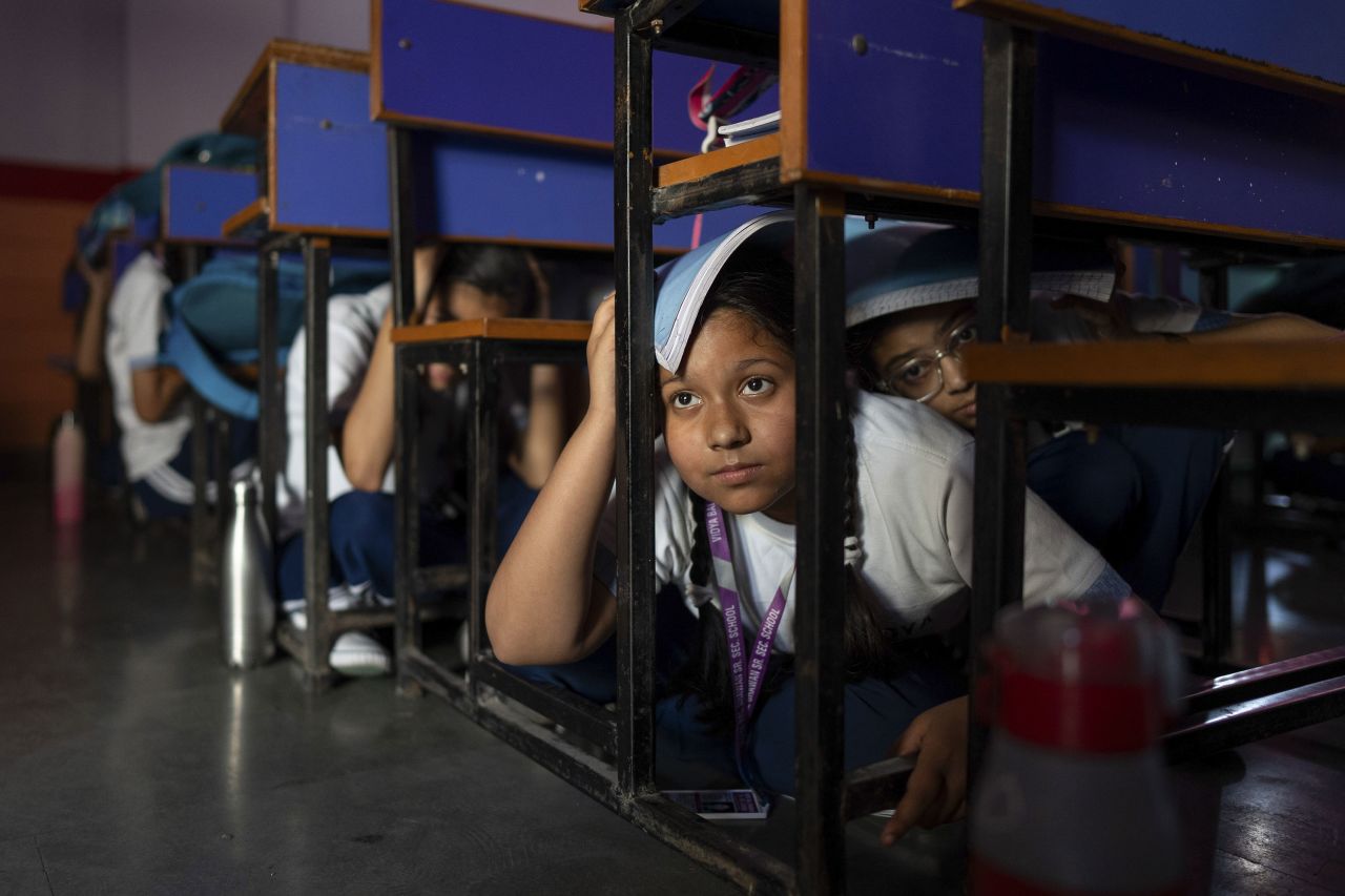 Students hide under desks during a safety drill inside a school in New Delhi on Wednesday.