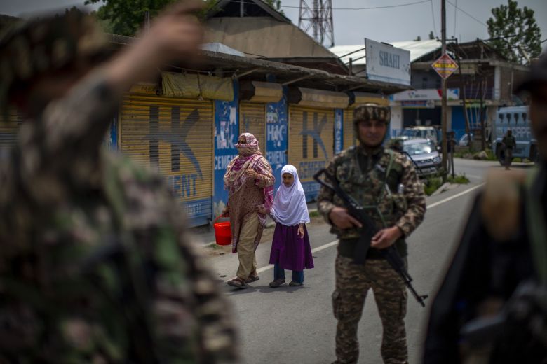 A Kashmiri Muslim woman along with a girl was allowed to cross the restricted area as Indian paramilitary soldiers stand guard on May 7, 2025 in Wuyan, south of Srinagar, India.