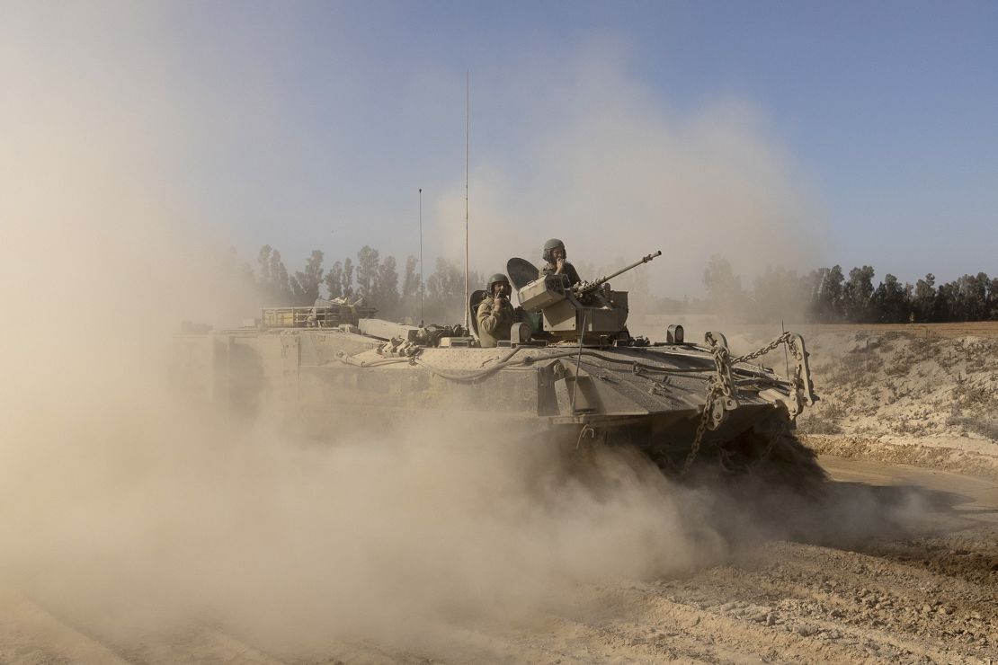 Israeli soldiers stand at armored carriers as they move near the border with the Gaza Strip on May 8, as seen from their position on the Israeli side of southern Israel.
