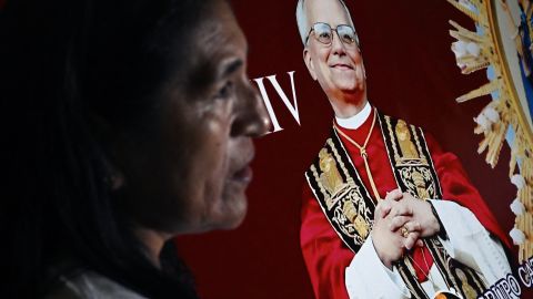 TOPSHOT - A woman stands next to the image of Robert Francis Prevost, who became Pope Leo XIV on May 8, 2025, in front of the cathedral of Chiclayo in northern Peru on the day of his election as the Catholic Church's 267th pontiff. The US-born pontiff, close to Pope Francis, became a Peruvian national in 2015 and devoted more than 20 years as a missionary in Peru. (Photo by ERNESTO BENAVIDES / AFP) (Photo by ERNESTO BENAVIDES/AFP via Getty Images)