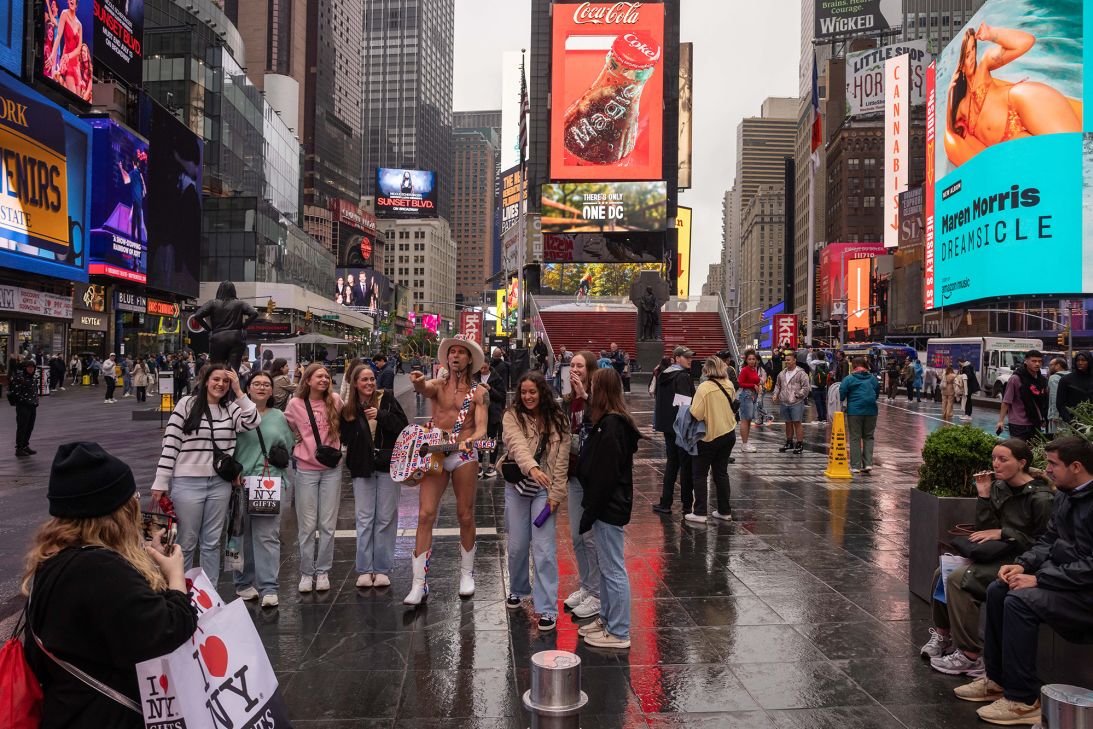 Tourists take a photo with the Naked Cowboy in Times Square on May 9, 2025. New York City officials cut their forecast for the number of international tourists this year by 17%, saying President Trump's hard-line policies on immigration are deterring visitors.