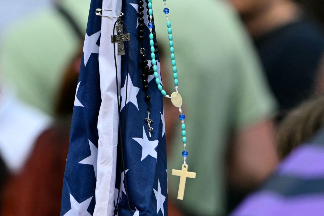 A rosary hangs on an American flag as people gather in St Peter's Square.