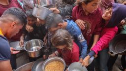 Palestinos se abalanzan para conseguir una ración de comida caliente de un comedor social instalado en el campus de la Universidad Islámica de la Ciudad de Gaza el 12 de mayo de 2025.