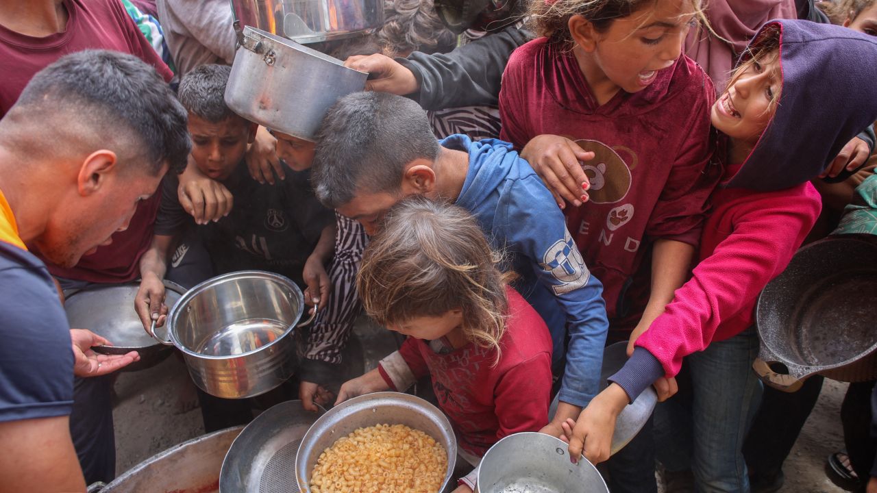 Palestinos se abalanzan para conseguir una ración de comida caliente de un comedor social instalado en el campus de la Universidad Islámica de la Ciudad de Gaza el 12 de mayo de 2025.