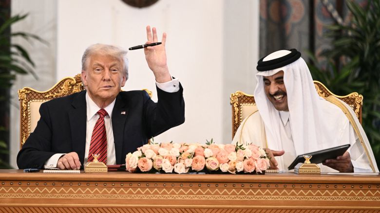 TOPSHOT - Qatar's Emir Sheikh Tamim bin Hamad al-Thani (R) reacts as US President Donald Trump raises his pen during a signing ceremony at the Royal Palace in Doha on May 14, 2025. Trump touched down at Hamad International Airport in Doha, with relations between the two governments in the spotlight over Qatar's offer to Trump of a $400 million luxury aircraft to serve as a new Air Force One and then pass into his personal use. (Photo by Brendan SMIALOWSKI / AFP) (Photo by BRENDAN SMIALOWSKI/AFP via Getty Images)          