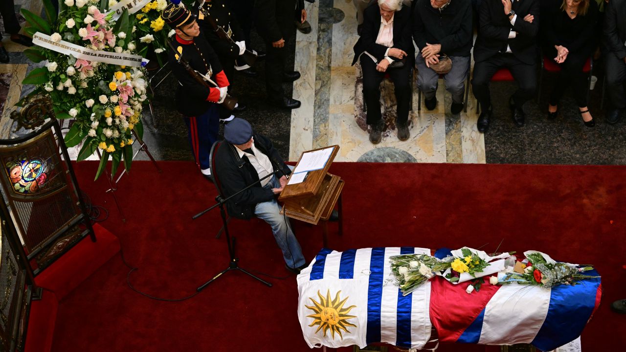 Uruguayan playwright, poet and journalist Mauricio Rosencof (L) reads poems as Uruguay's former vice president and the wife of the late Uruguay's former president (2010-2015) Jose 'Pepe' Mujica, Lucia Topolansky, Uruguay's President Yamandu Orsi (2nd R) and Uruguay's Vice-President Carolina Cosse (R) look on during Mujica's wake at the Palacio Legislativo, in Montevideo, on May 15, 2025. For a second day, thousands of Uruguayans lined up to bid farewell to deceased former leader Jose "Pepe" Mujica, who lost a year-long battle against cancer on May 13, 2025. The 89-year-old erstwhile leftist guerrilla, who spent a dozen years behind bars for revolutionary activity, was famed for his humility and once known as the "world's poorest president". (Photo by Pablo PORCIUNCULA / AFP) (Photo by PABLO PORCIUNCULA/AFP via Getty Images)          