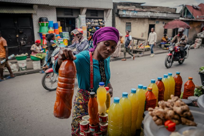 A vendor sells bottles of palm oil along with tomatoes and other food products at Birere market in Goma on May 15, 2025