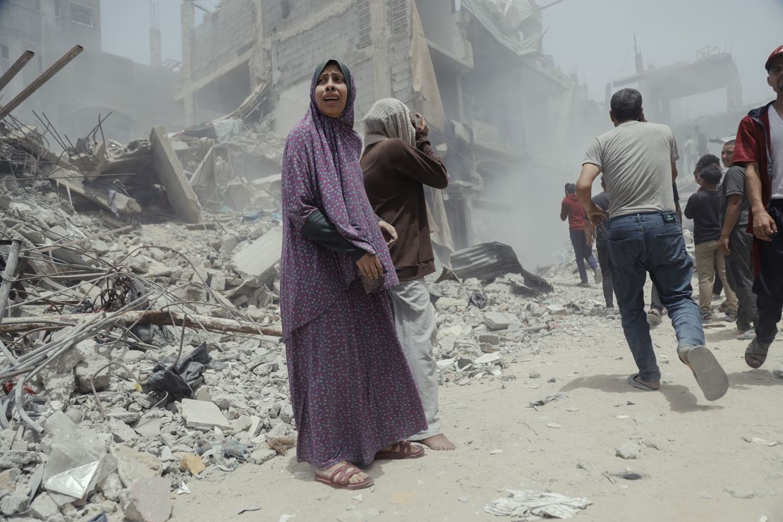 Palestinian civilians walk past collapsed structures and debris in the aftermath of an Israeli airstrike in Gaza, on Saturday.