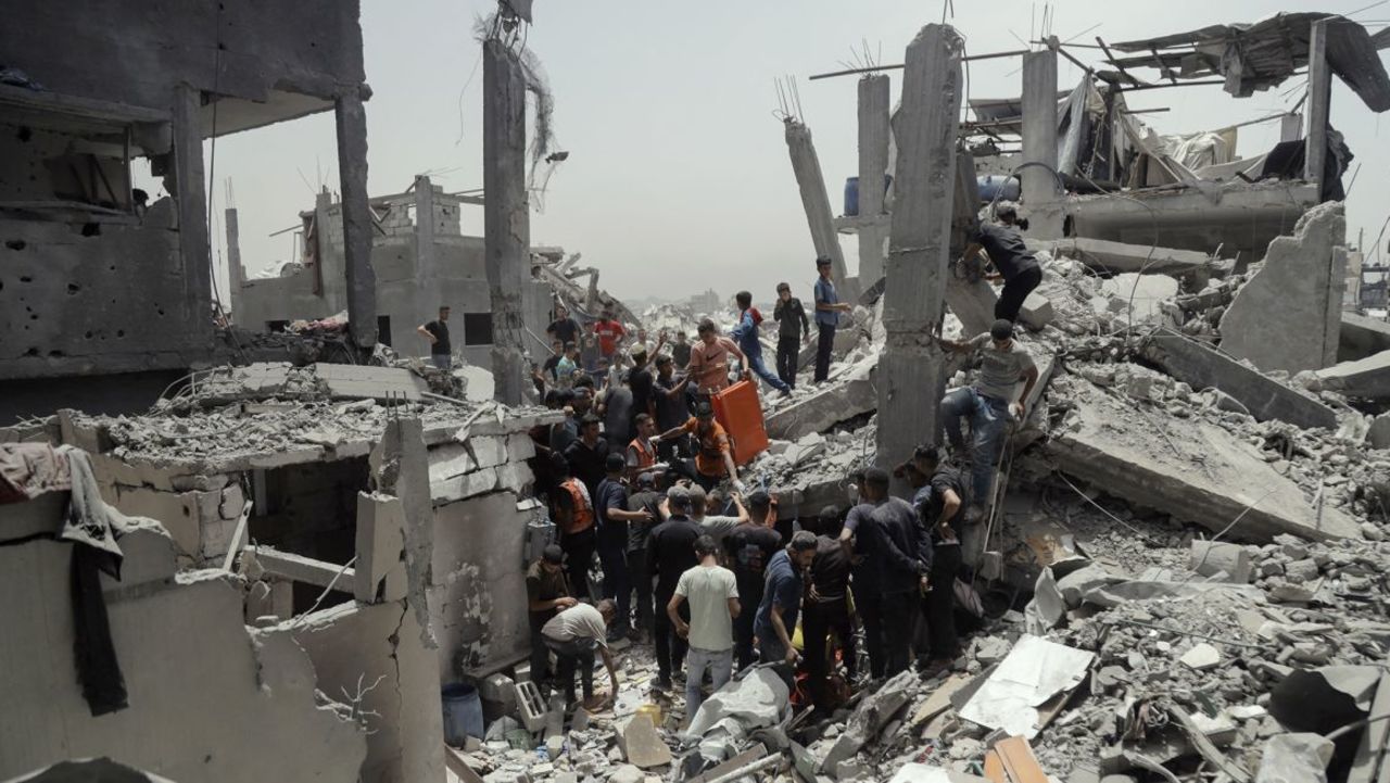 Multitudes se congregan sobre las ruinas de edificios residenciales mientras los equipos de búsqueda y rescate continúan sus labores en Gaza el sábado tras los mortales ataques de Israel.