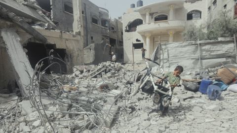A child pulls a broken stroller across a pile of rubble in Gaza City, Palestine, on May 18, 2025. Israeli airstrikes left widespread destruction in residential neighborhoods overnight. (Photo by Youssef Alzanoun / Middle East Images / Middle East Images via AFP) (Photo by YOUSSEF ALZANOUN/Middle East Images/AFP via Getty Images)          