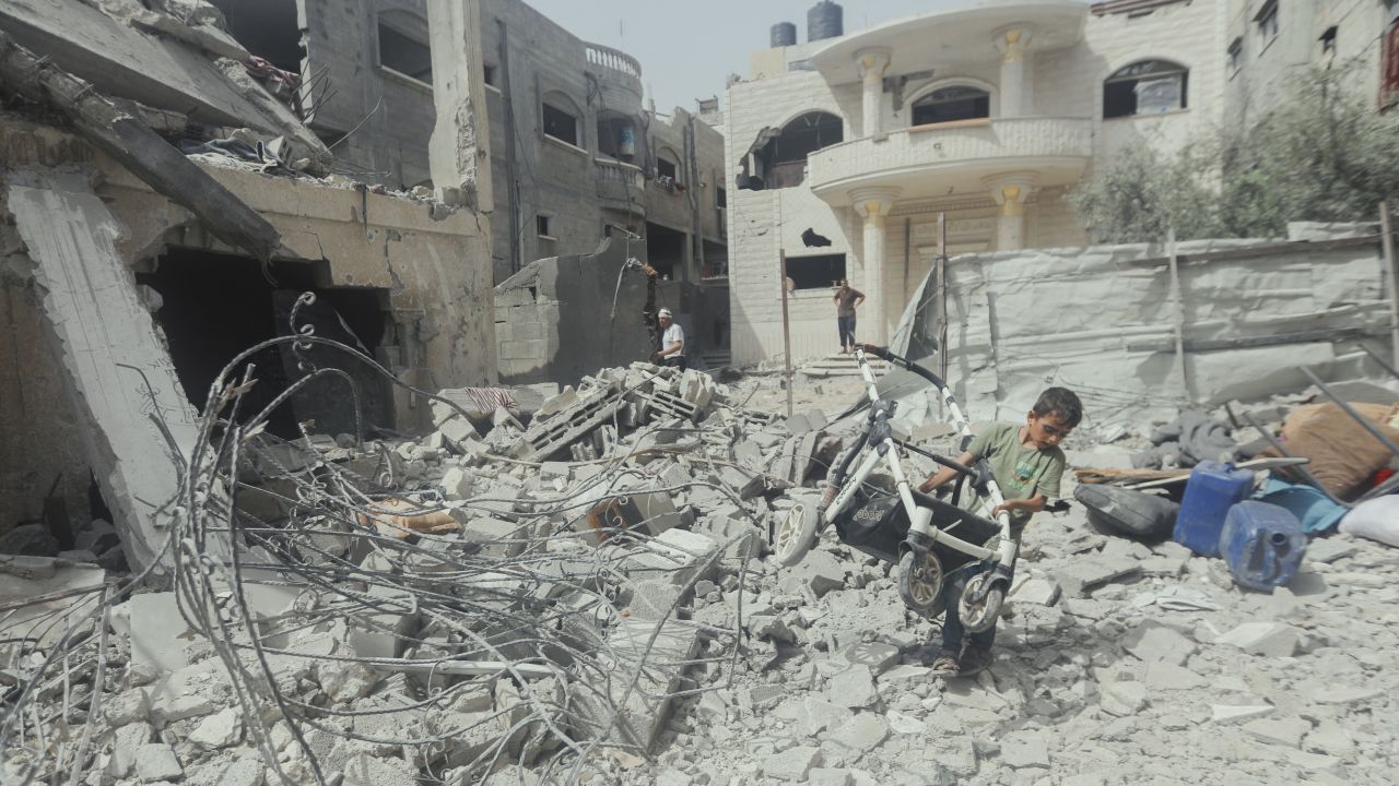 A child pulls a broken stroller across a pile of rubble in Gaza City, Palestine, on May 18, 2025. Israeli airstrikes left widespread destruction in residential neighborhoods overnight. (Photo by Youssef Alzanoun / Middle East Images / Middle East Images via AFP) (Photo by YOUSSEF ALZANOUN/Middle East Images/AFP via Getty Images)          