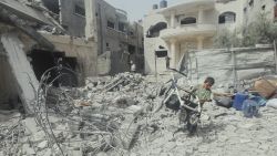 A child pulls a broken stroller across a pile of rubble in Gaza City, Palestine, on May 18, 2025. Israeli airstrikes left widespread destruction in residential neighborhoods overnight. (Photo by Youssef Alzanoun / Middle East Images / Middle East Images via AFP) (Photo by YOUSSEF ALZANOUN/Middle East Images/AFP via Getty Images)          