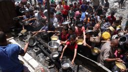 Palestinos desplazados se reúnen para recoger porciones de comida cocinada en un punto de distribución de caridad en Jabalia, en el norte de Gaza, el 19 de mayo de 2025.