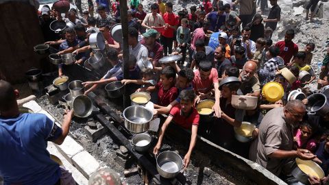 Palestinos desplazados se reúnen para recoger porciones de comida cocinada en un punto de distribución de caridad en Jabalia, en el norte de Gaza, el 19 de mayo de 2025.