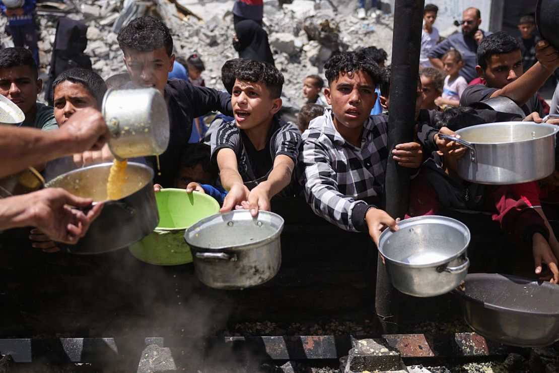 Palestinos desplazados se reúnen para recolectar porciones de comida en una distribución benéfica en Jabalia, al norte de Gaza, el 19 de mayo de 2025.