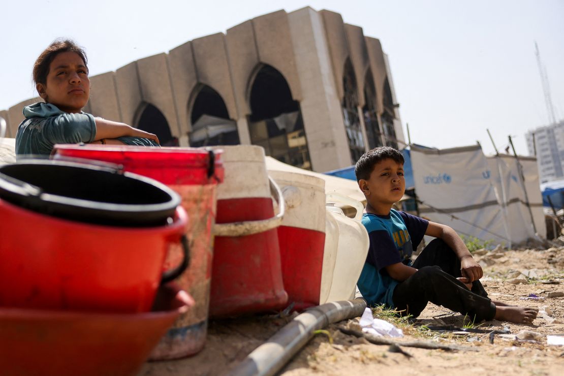 Children sit with plastic buckets as displaced Palestinians collect water in Gaza City. As its expanded military operation continues, Israel Israel faces mounting pressure including from the United States to end the aid blockade it imposed on March 2.