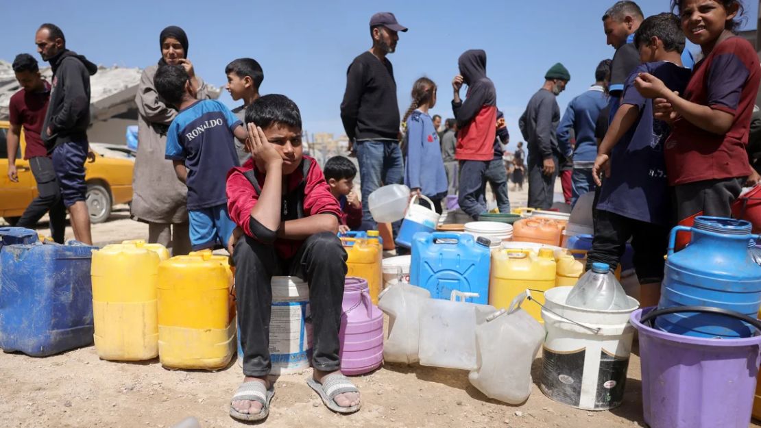 Palestinos intentan recoger agua en un campamento para desplazados en la ciudad de Gaza, el 20 de mayo de 2025, en medio de la operación militar israelí en el enclave.