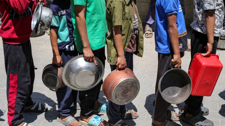 Palestinos se reúnen para recibir una comida caliente en un punto de distribución de alimentos en el campamento de refugiados de Nuseirat, en el centro del enclave de Gaza, el 21 de mayo de 2025. Los gazatíes esperaban desesperadamente suministros vitales el 21 de mayo después de que Israel anunciara que había permitido la entrada de docenas de camiones de la ONU, pero se enfrentaba a una creciente presión internacional para aumentar el flujo de ayuda y abandonar su intensificada campaña militar.