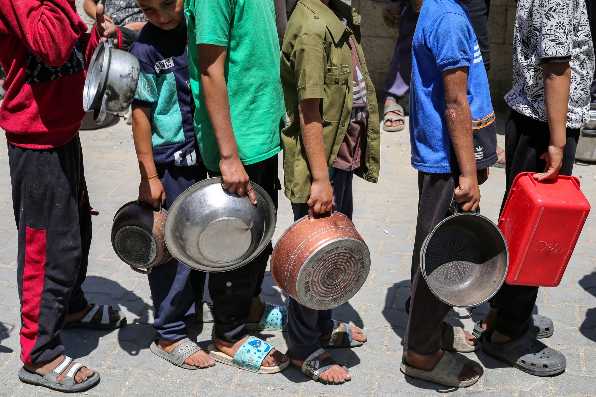 Los palestinos se reúnen para recibir una comida caliente en un punto de distribución de alimentos en el campamento de refugiados de Nuseirat, en el centro del enclave de Gaza, el 21 de mayo de 2025.