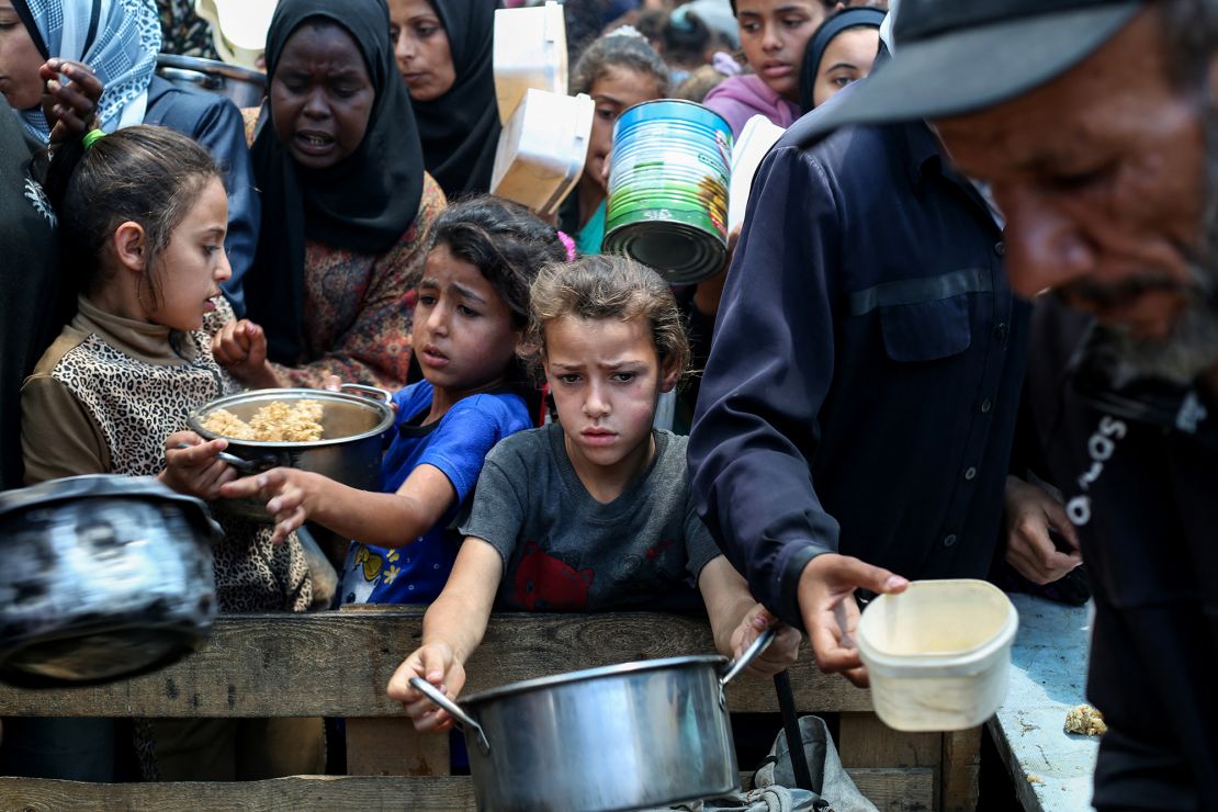 Palestinians gather to receive a hot meal at a food distribution point at a refugee camp in central Gaza on May 21.