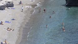 Tourists enjoy the summer sun at the sandy beach at Preveli, a popular tourist destination in the Mediterranean sea with the freshwater river, the palm tree forest and the entrance of the rocky gorge. The beach has crystal clear waters and is connected by a ferry boat to nearby town and beach. The famous palm tree forest has the native Phoenix theophrasti, the Cretan date palm honoring the ancient Greek philosopher and naturalist Thoephrastus. Preveli Beach, Crete, Greece on May 11, 2025 (Photo by Nicolas Economou/NurPhoto via Getty Images)