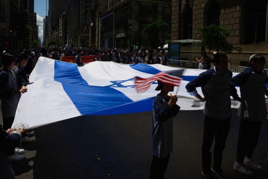 A participant waves an American flag while holding a large Israeli flag during New York City's Celebrate Israel Parade on May 18, 2025.