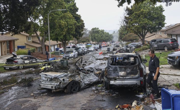 Investigadores inspeccionan el lugar donde una avioneta se estrelló en una calle residencial de San Diego.
