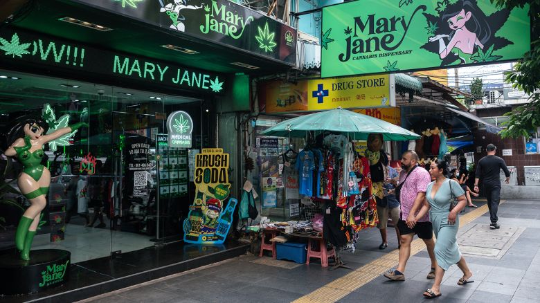 People walk past the Mary Jane cannabis dispensary in Bangkok on May 23, 2025.