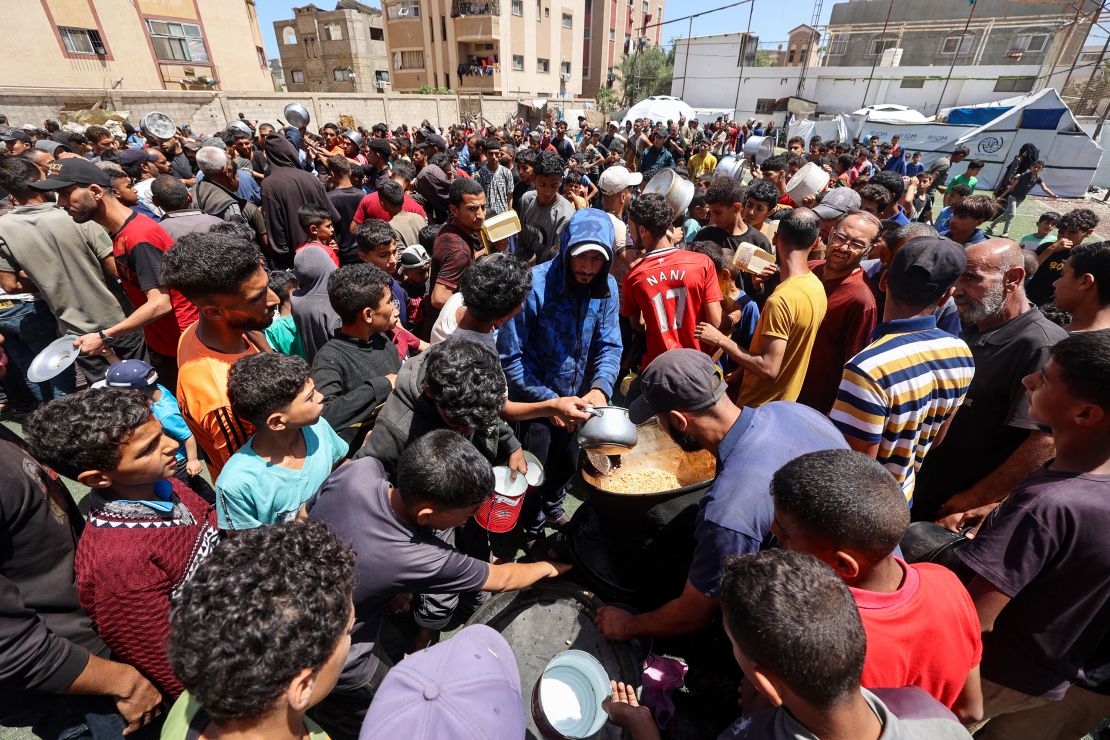 Palestinians gather to receive a hot meal at a food distribution point in the Nuseirat camp for refugees on May 24.