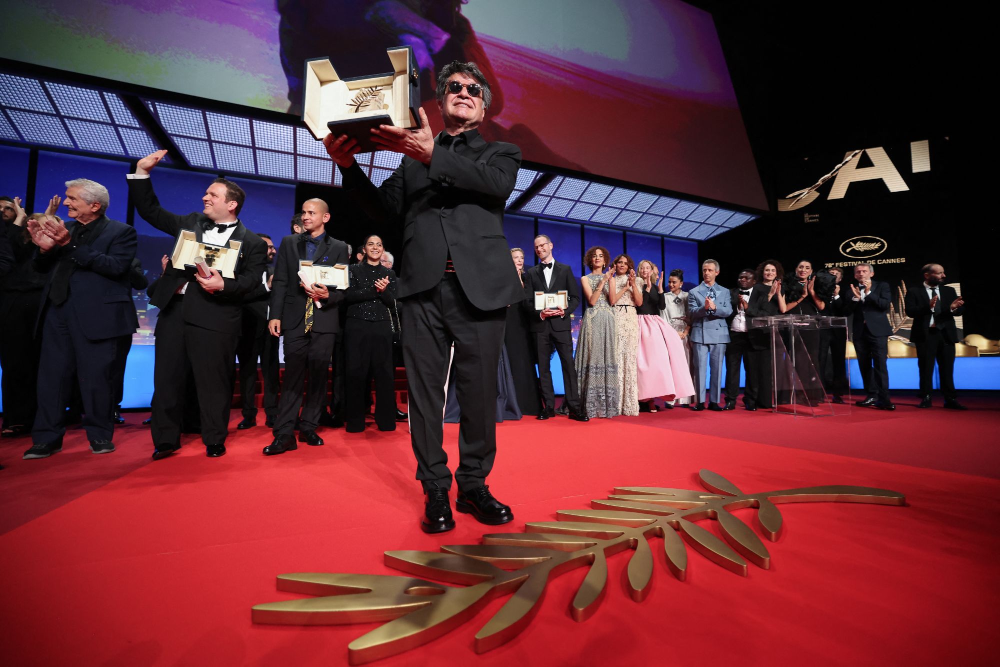 Iranian director, screenwriter and producer Jafar Panahi celebrates after winning the Palme d'Or during the closing ceremony at the 78th edition of the Cannes Film Festival on May 24, 2025.