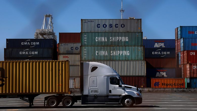 A truck drives by stacked shipping containers at the Port of Oakland on May 20 in Oakland, California. The Port of Oakland saw a 14.7% decrease in overall cargo volume in April after the Trump administration's tariffs were enacted.