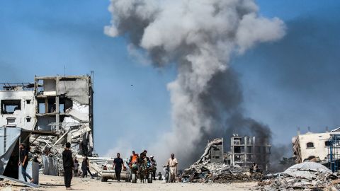 People move past destroyed buildings as smoke billows following an Israeli strike in Jabalya, in northern Gaza, on May 25.