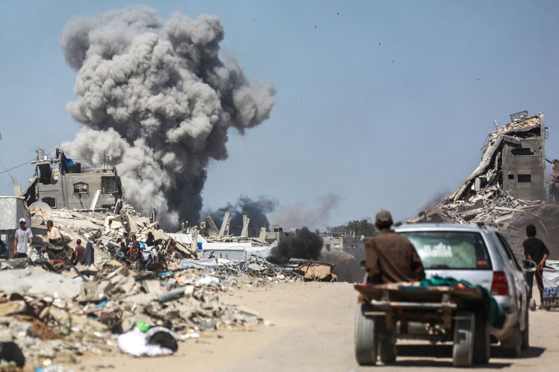People watch as smoke billows into the sky, following an Israeli strike in Jabalia, in the northern Gaza Strip on May 25.