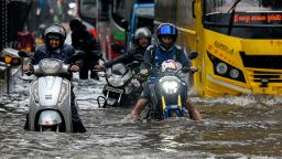 Commuters wade through a flooded street after heavy rain showers in Mumbai on May 26.