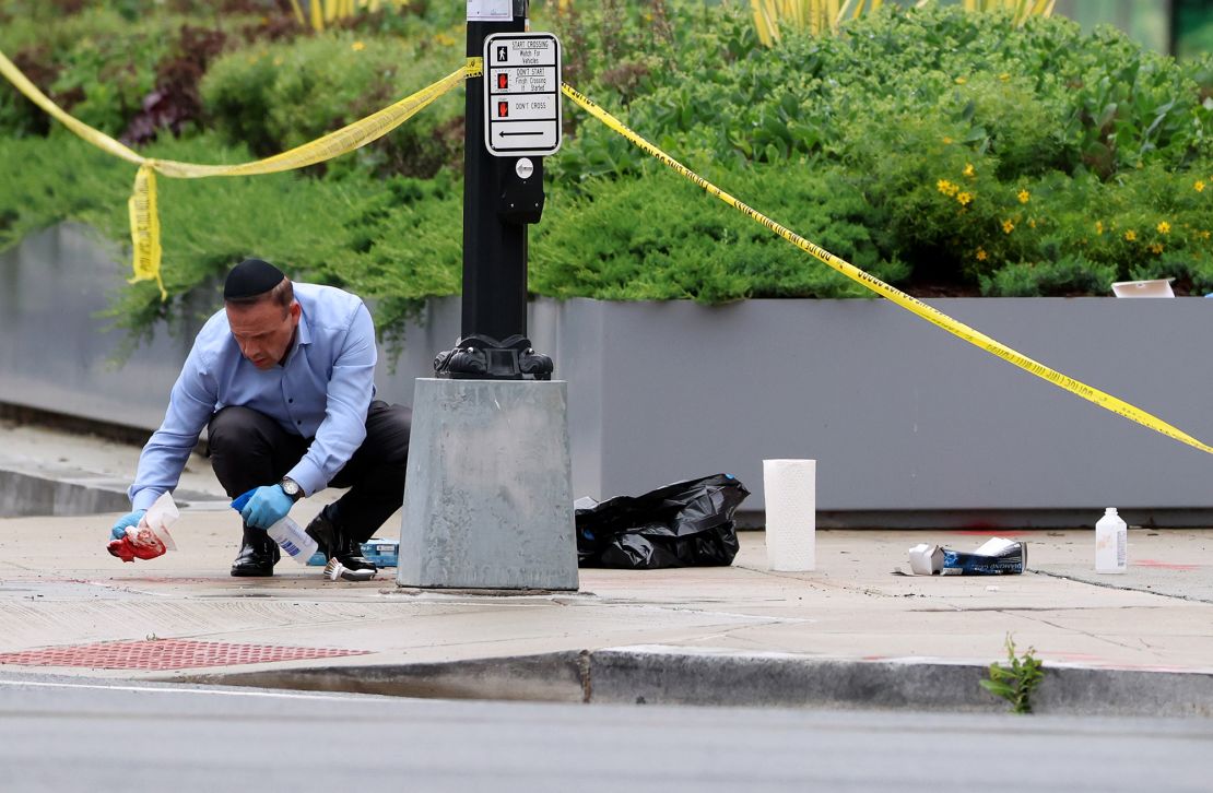 An embassy official cleans blood off the sidewalk at the shooting location outside of the Lillian and Albert Small Capital Jewish Museum on May 22, 2025 in Washington, DC.