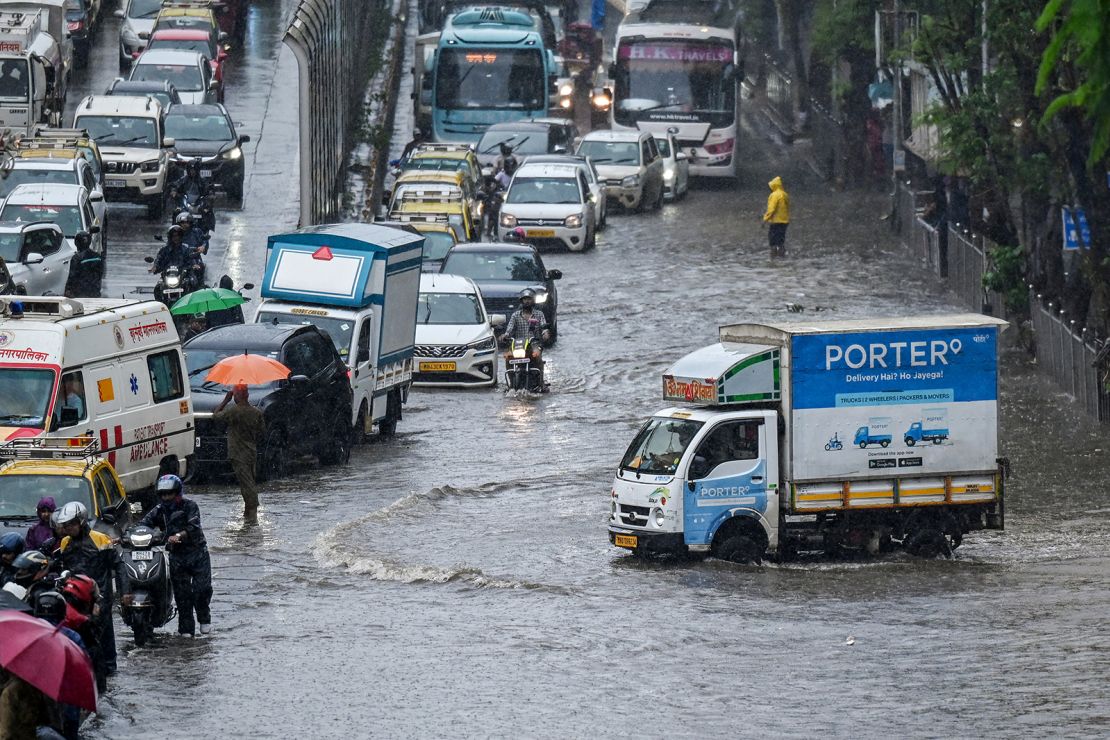 Commuters lie stuck in traffic as they wade through a flooded street after heavy rain showers in Mumbai on May 26.